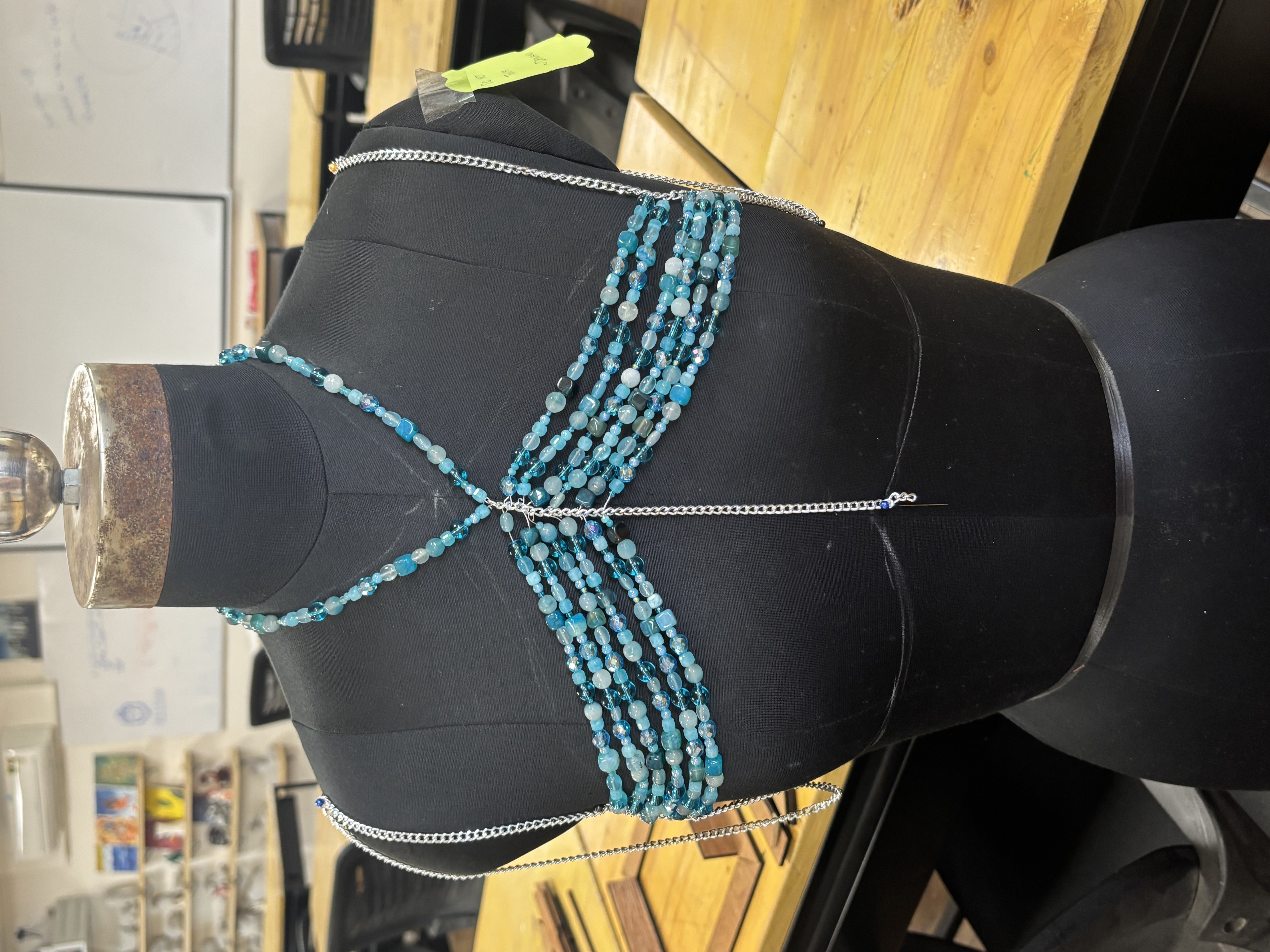 Later stage of the beaded garment, multiple bead strands built up across a mannequin