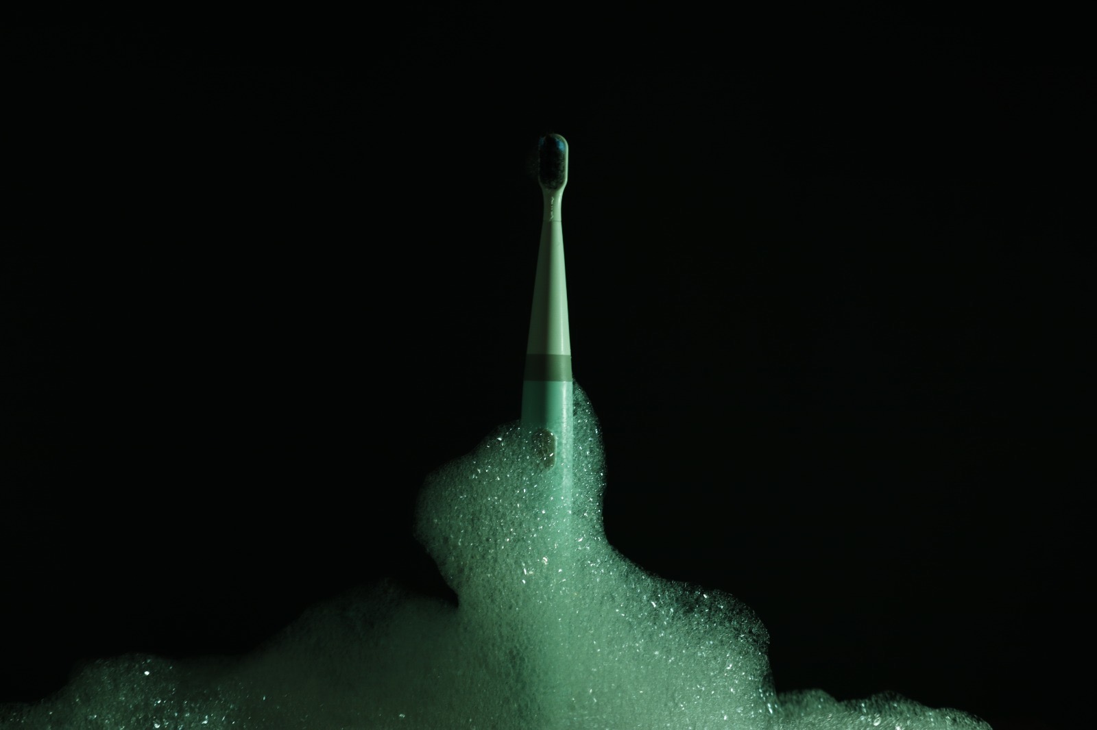 TUSK toothbrush emerging from green-lit foam against a black background, an early colour exploration