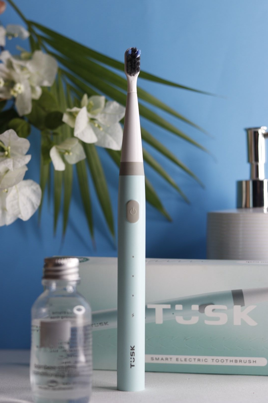 Final TUSK lifestyle photograph on a cobalt-blue bathroom countertop with flowers and packaging