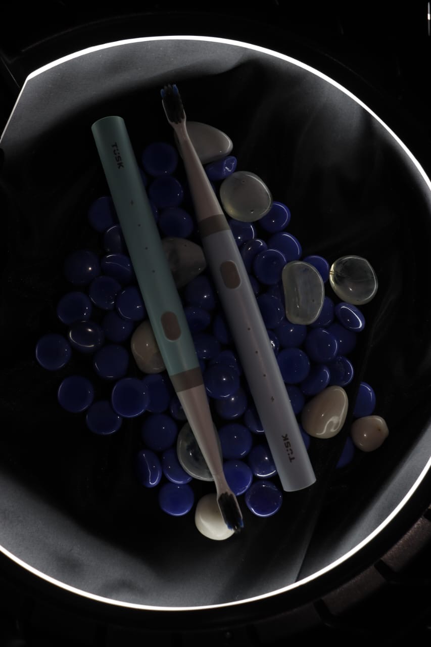 Two TUSK toothbrushes resting on cobalt-blue glass pebbles, representing the cobalt blue concept