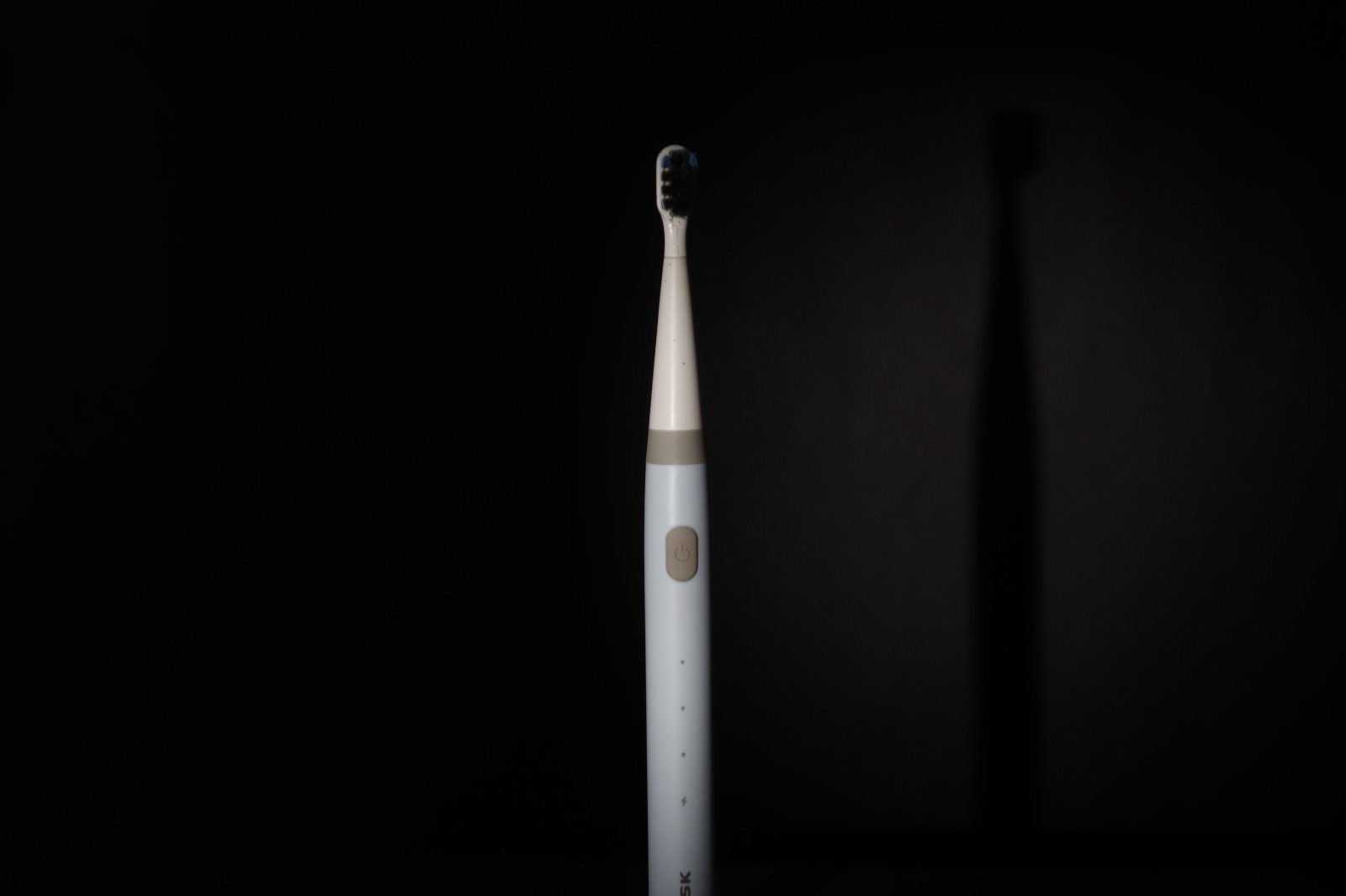 TUSK toothbrush lit against a plain black background, a contrast test shot